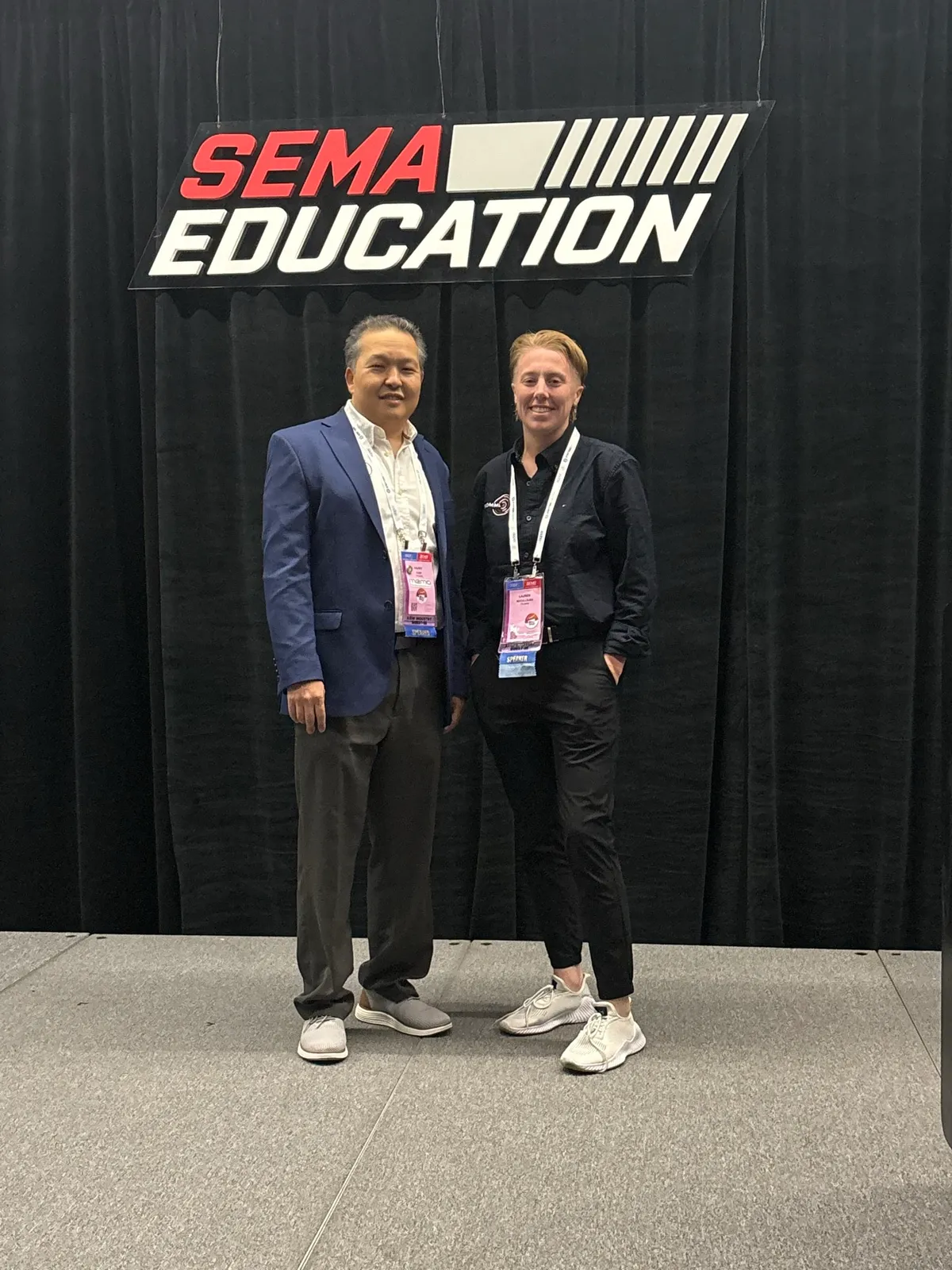 Lauren McCullough with a colleague at the SEMA Show education backdrop